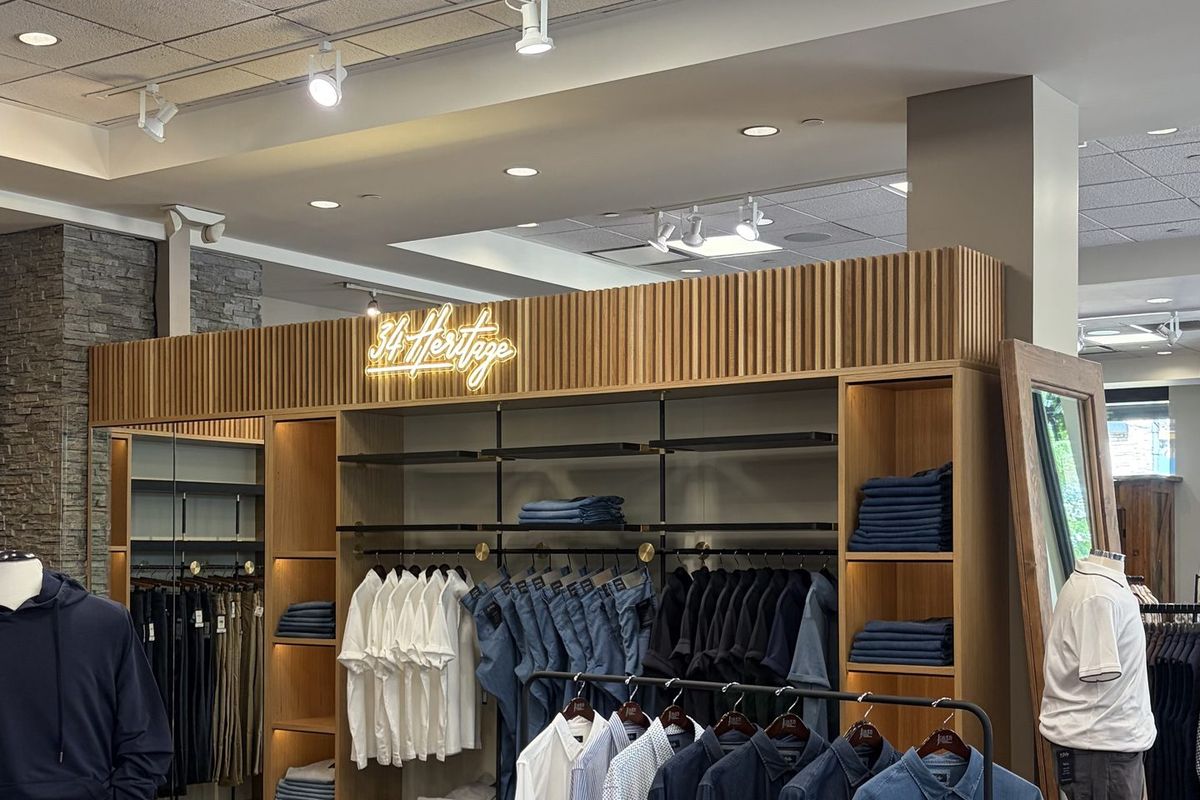 J David's Custom Clothiers sales floor with track lighting over a lit display wall